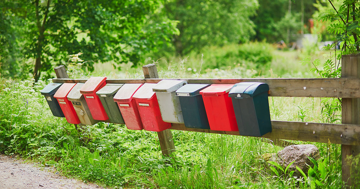 Rivi postilaatikkoja soratien varrella kesäisen vihreässä ympäristössä